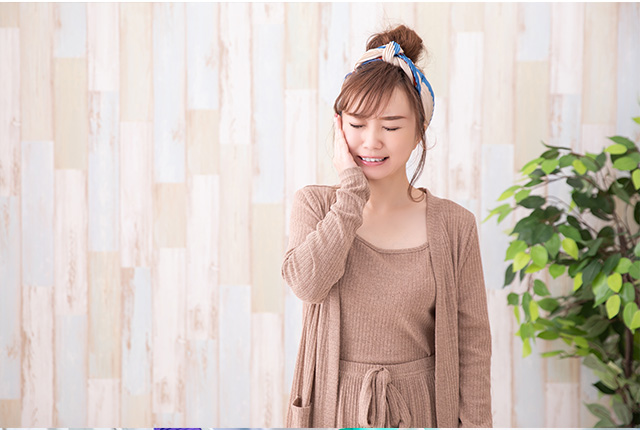 頬に手を当て痛がる女性