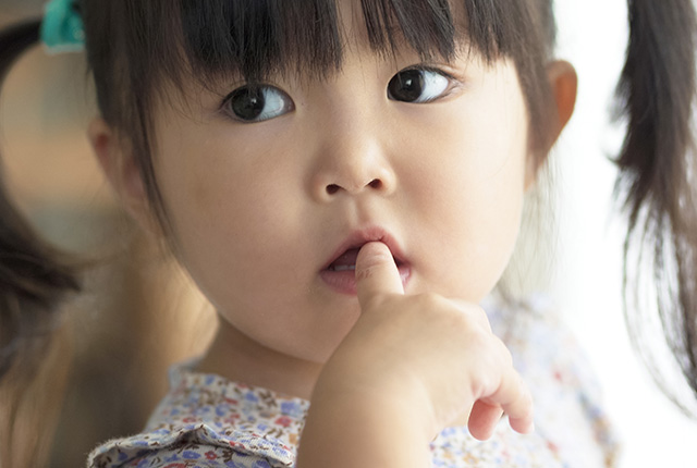 人差し指を加える女の子の顔