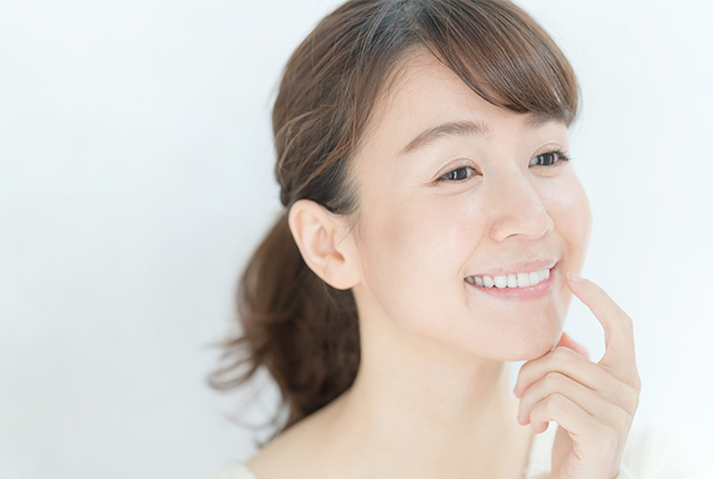 人差し指を口元にあて笑う女性