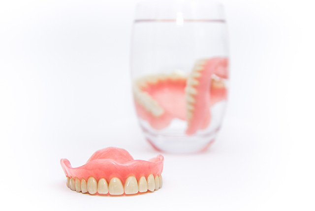 入れ歯とコップで洗浄してる入れ歯