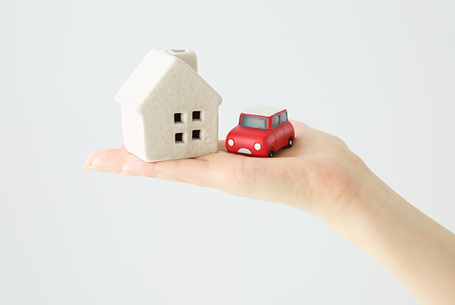 手のひらに家と車の模型を載せてる様子