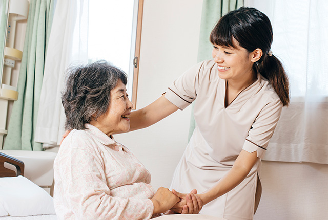高齢者の背中を起こす介護スタッフ
