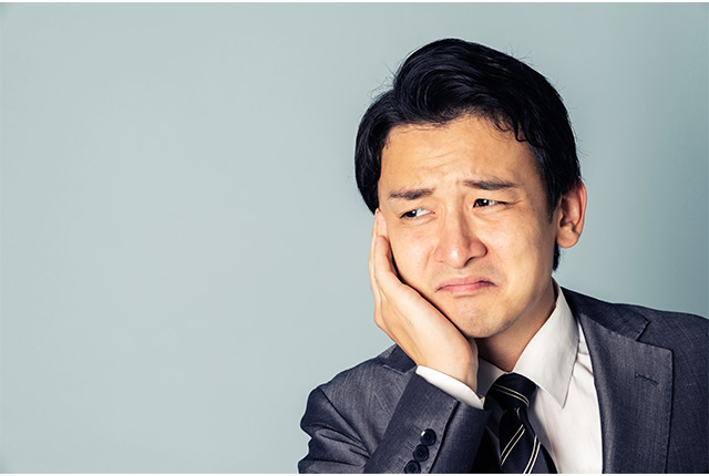 頬を抑え歯を痛そうにする男性