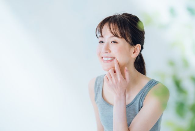 口元に指をそえ歯を見せて笑う女性